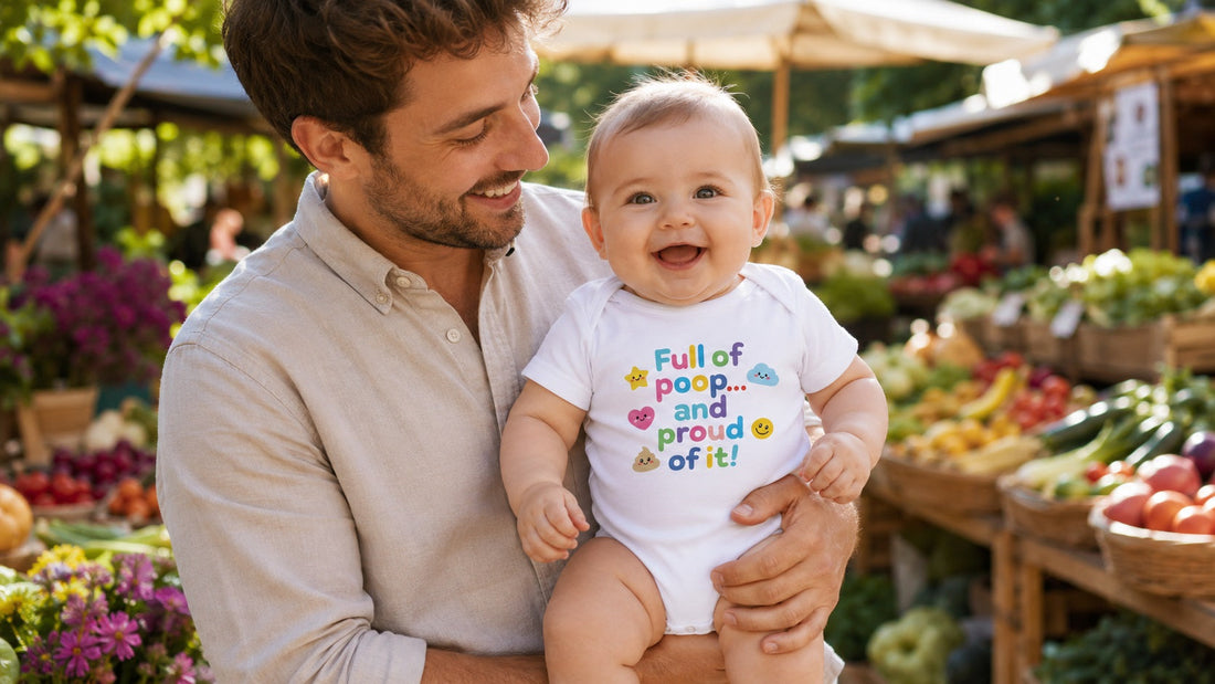 Vater mit lächelndem Baby in einem lustigen Bio-Baumwoll-Strampler auf einem sonnigen Bauernmarkt